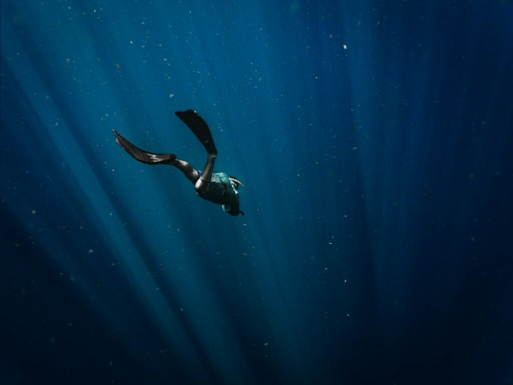 man in black wetsuit swimming in blue water